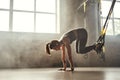 Doing TRX exercises. Young athletic woman in sports clothing training legs with trx fitness straps in the gym. Royalty Free Stock Photo