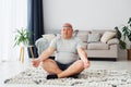 Doing yoga exercises. Funny overweight man in casual clothes is indoors at home Royalty Free Stock Photo