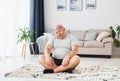 Doing yoga exercises. Funny overweight man in casual clothes is indoors at home Royalty Free Stock Photo