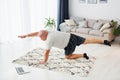 Doing yoga exercises. Funny overweight man in casual clothes is indoors at home Royalty Free Stock Photo