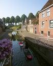 Girls on surf boards paddle in canal of old town dokkum in dutch province of friesland on sunny summer morning Royalty Free Stock Photo