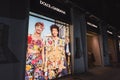 Dolce & Gabbana shop`s exterior at night, front windows with clothes and a poster showing women models and inhabited by alive geck