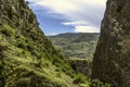 Hills in Garni gorge with flowering shrubs and green grass against a blue sky covered with clouds Royalty Free Stock Photo