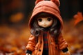 a doll dressed in an orange coat standing in a field of autumn leaves