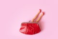 Doll legs in red shoes sticking out of the purse top view. Creative female shopping or finanse concept