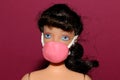 doll with a pink mask on a pink background