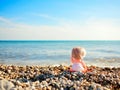 Doll sitting on beach and pointing to the sea