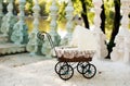 Doll's pram. Vintage doll stroller placed on the stairs to a beautiful lake. Retro cart dolls made of rattan and white lace.