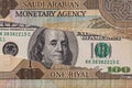 100 dollar banknote through torn  Saudi riyal banknote Royalty Free Stock Photo