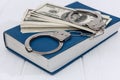 Dollar banknotes with handcuffs on blue book Royalty Free Stock Photo