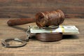 Dollar banknotes, handcuffs and judge gavel on wood table