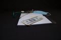 Dollar banknotes lie on a white sheet with a stethoscope and a medical mask on a black background. Stethoscope of a Royalty Free Stock Photo