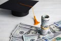 Dollar banknotes and student graduation hat on wooden background. Tuition fees concept Royalty Free Stock Photo