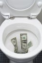 US one dollar bills flushed down a toilet, wasting money concept