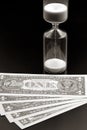 Dollar bills lie near the hourglass. Time is money. The salary. Business solutions in time. Hourglass time measurement