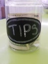 Tip jar in cafe with money inside on checkout counter