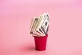 Dollar bills in a red bucket on a pink background. Money saving concept Royalty Free Stock Photo