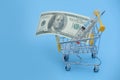 Dollar bills roll and thermometer in shopping cart on shopping. Medicine concept with copy space Royalty Free Stock Photo