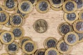 1 dollar coins in the middle of several 1 real coins on a wooden