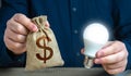 Dollar money bag and burning idea light bulb in the hands of a man. Royalty Free Stock Photo