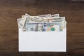 Dollar money in white envelop on wooden background.