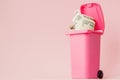 Dollars bank notes in pink rubbish bin on pink background Royalty Free Stock Photo