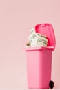 Dollars bank notes in pink rubbish bin on pink background Royalty Free Stock Photo