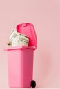 Dollars bank notes in pink rubbish bin on pink background Royalty Free Stock Photo