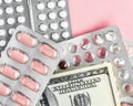 Dollars banknote and pills in blister on a pink background, rising prices of healthcare system. Vaccine and antibiotic for