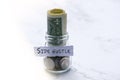 Dollars bill and coins in a jar with stick note with text written SIDE HUSTLE