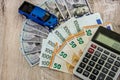 Dollars, euros, a calculator and a toy blue car on a wooden background Royalty Free Stock Photo