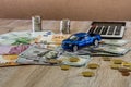 Dollars, euros, coins, a calculator and a toy blue car on a wooden background Royalty Free Stock Photo