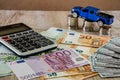 Dollars, euros, coins, a calculator and a toy blue car on a wooden background Royalty Free Stock Photo