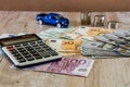 Dollars, euros, coins, a calculator and a toy blue car on a wooden background Royalty Free Stock Photo