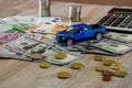 Dollars, euros, coins, a calculator and a toy blue car on a wooden background Royalty Free Stock Photo