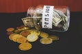 Dollars in a glass jar and coins on black. Saving money. Pension concept. Royalty Free Stock Photo