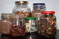 Dollars in a glass jar, among other jars of cereals and dried fruits. Financial stock Royalty Free Stock Photo