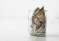 Dollars in a glass jar on a white wooden table