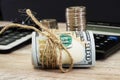 Dollars rolled into a roll on the background of a calculator and stacks of coins. Close-up.