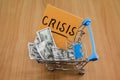 Dollars in a shopping cart and a sticker with the words `crisis`. The concept of economic crisis. Drops in income and solvency.