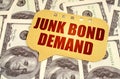 On the dollars is a sign with the inscription - JUNK BOND DEMAND