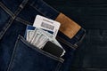 Dollars, smart, passport and plane ticket in your pocket jeans on black wooden background