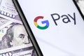 Dollars and smartphone with Google Pay logo on the screen digital wallet service by Google. Royalty Free Stock Photo