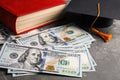 Dollars, student graduation hat and book. Tuition payments concept Royalty Free Stock Photo