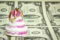 Dollars and wedding cake with rings Royalty Free Stock Photo