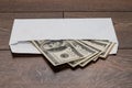 Dollars in a white envelope on a wooden background. Bribery concept. Salary in envelopes.