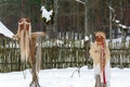 Dolls of old man with beard and young girl with braid in MeteÃâ i mumming masks and costumes staying in the snowy yard