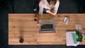 Dolly shot of top down view of casually-dressed woman talking in videochat using smartphone in office in front of the