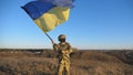 Dolly shot of young man in military uniform waving flag of Ukraine against blue sky. Male ukrainian army soldier lifted Royalty Free Stock Photo