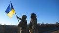 Dolly shot of young woman and man in military uniform lifted flag of Ukraine against blue sky. Female and male soldier Royalty Free Stock Photo